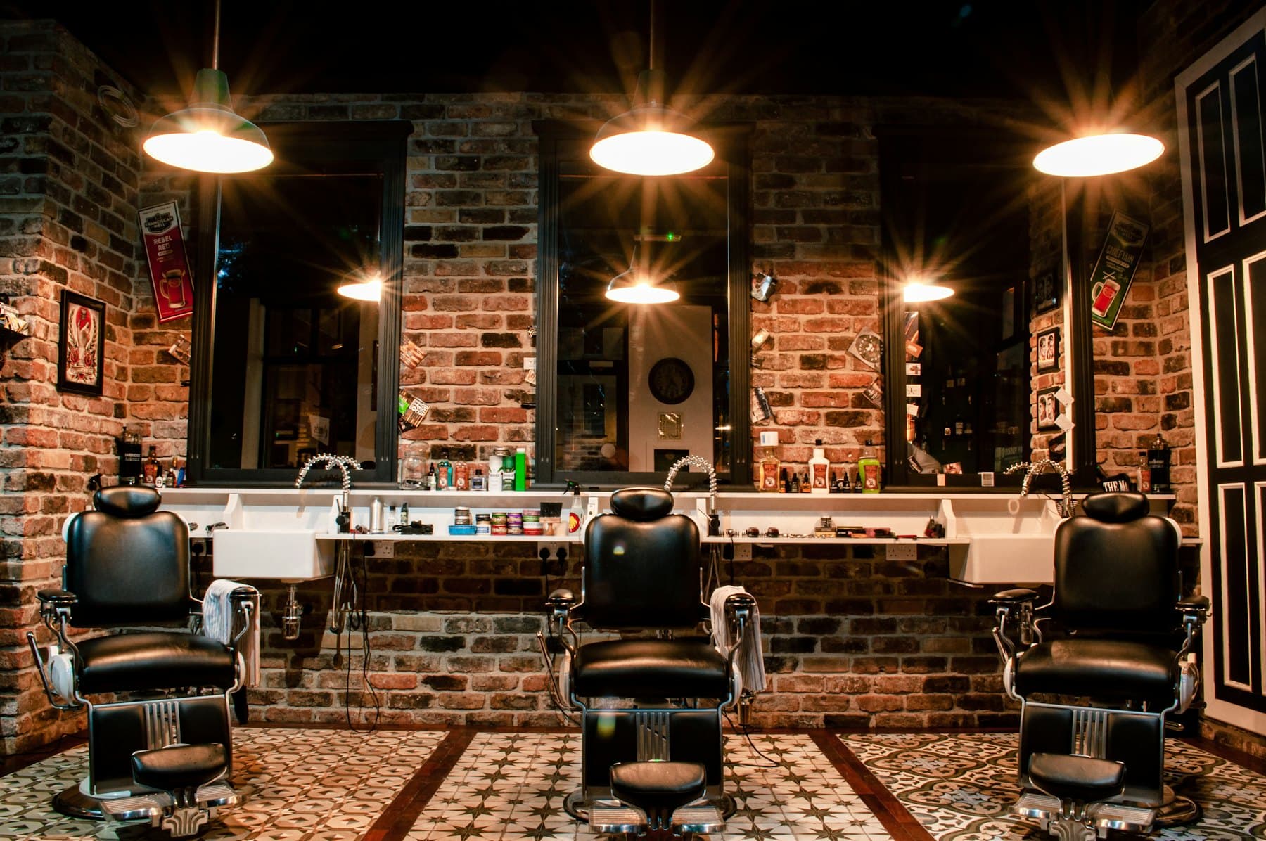 Salão da barbearia: três cadeiras, espelhos e luz quente